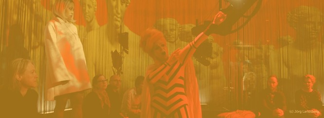 Szenenfoto aus der Oper I.Tha.ka. Darüber ein gelbes Overlay.