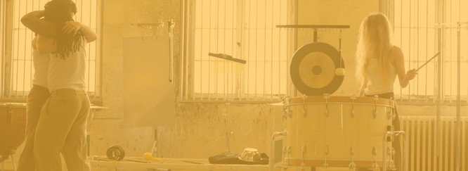 Eine Performance von zwei Tänzer:innen und einer Percussionistin, Foto mit gelbem Overlay