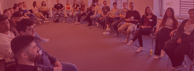 Eine große Gruppe Stipendiatinnen im Stuhlkreis im Workshopraum, Foto mit rotem Overlay